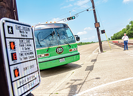 Bus passing through an intersection with a pedestrian standing nearby.