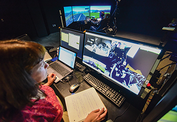 A researcher monitoring a participant during a driving simulation.