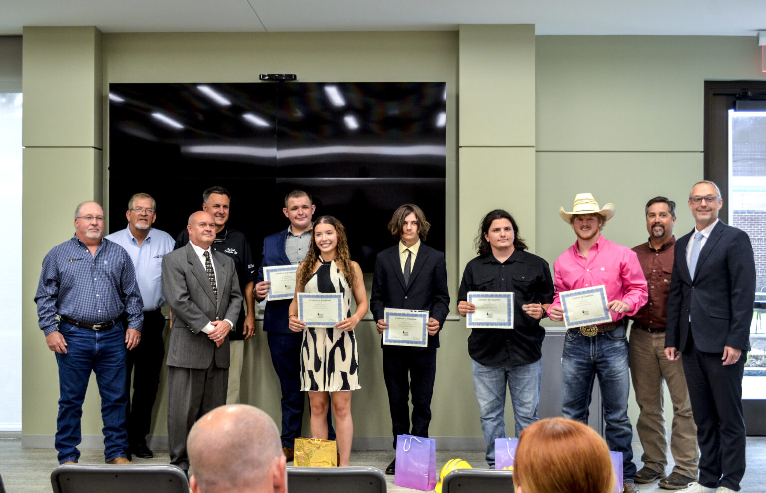 Graduates of the Highway Construction Workforce Partnership pose for a picture, holding their graduation certificates.
