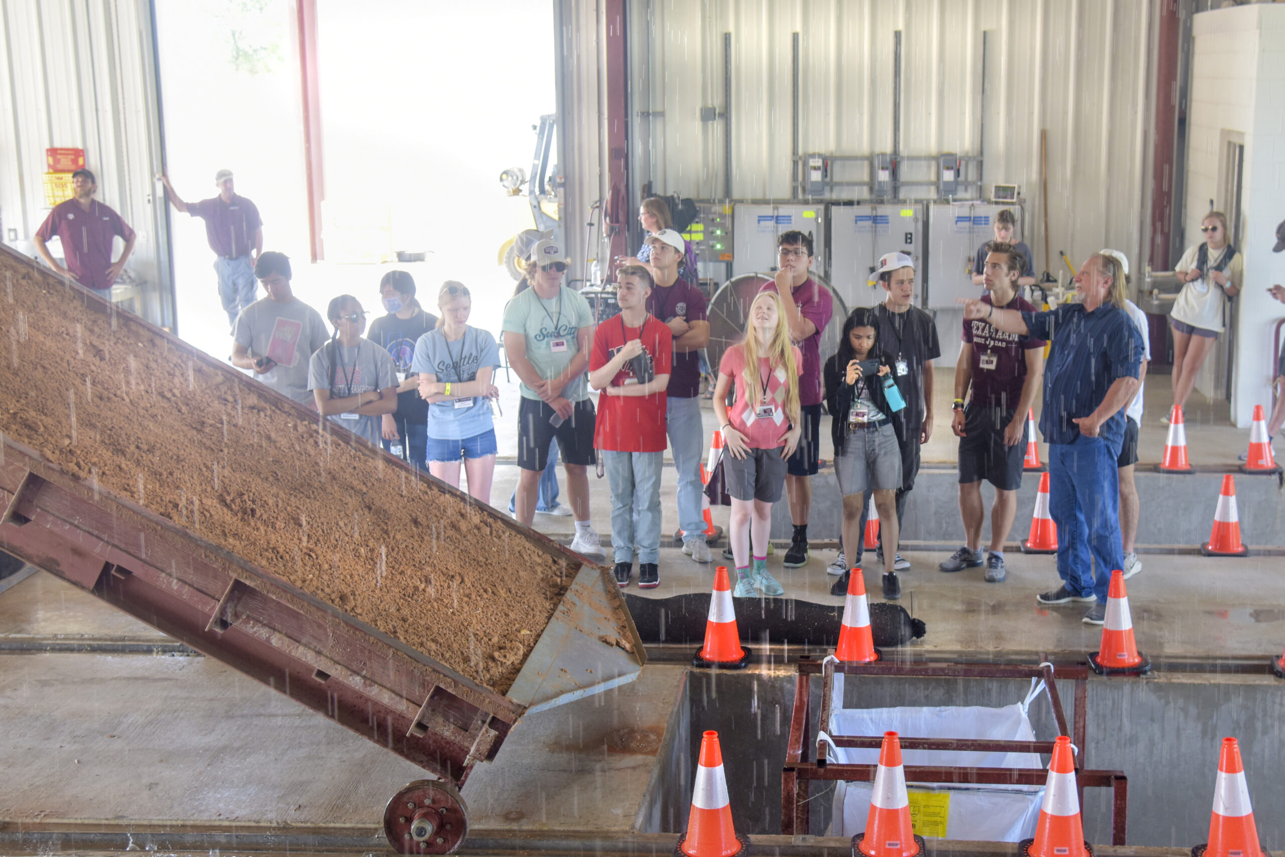 Students gather to observe the rainfall simulator in action.