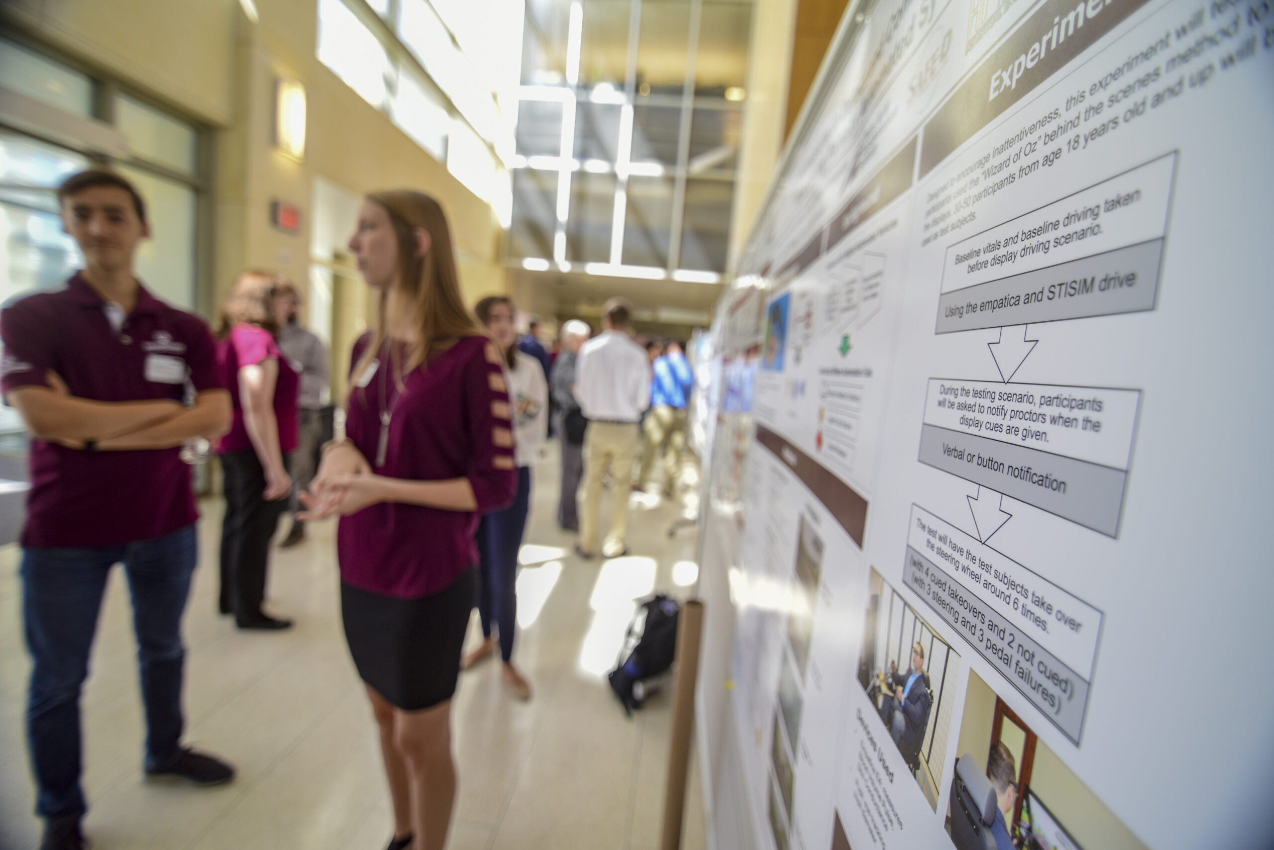 A student intern presents her poster to a crowd of onlookers.